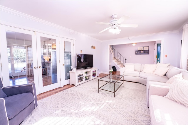 living area featuring ceiling fan, wood finished floors, french doors, ornamental molding, and stairway