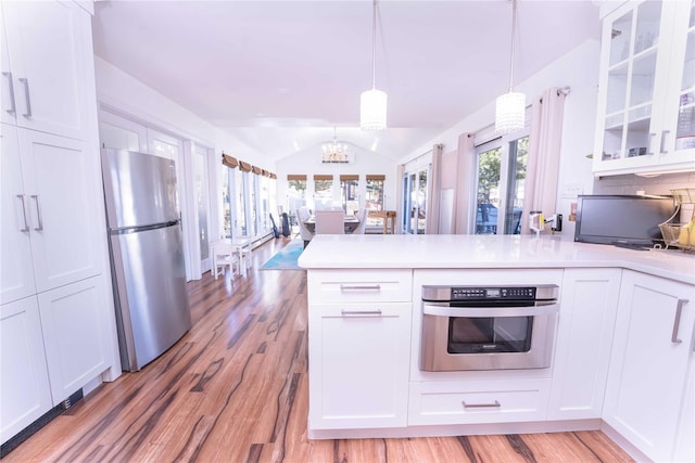 kitchen with a peninsula, white cabinets, stainless steel appliances, and lofted ceiling