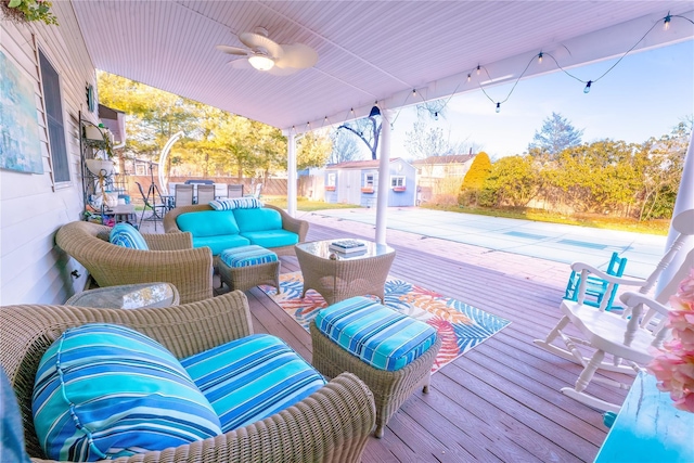 wooden deck featuring a ceiling fan, an outbuilding, fence, a shed, and outdoor lounge area