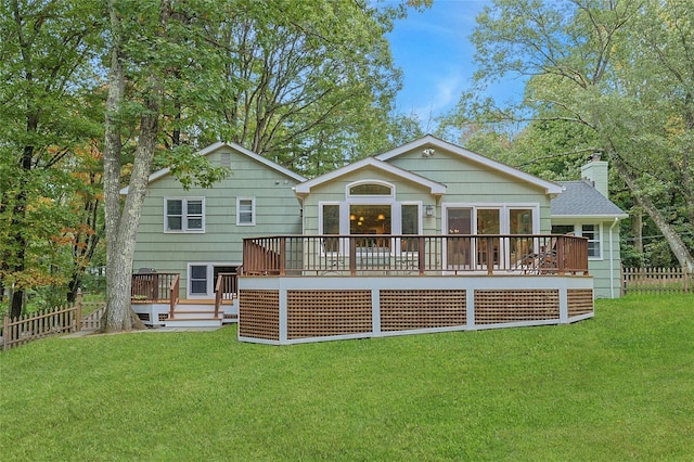 back of house featuring a deck, a lawn, a chimney, and fence