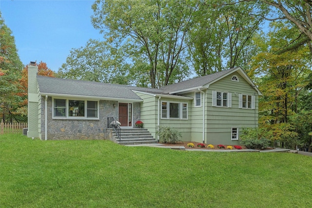 tri-level home featuring stone siding, a shingled roof, a chimney, and a front yard