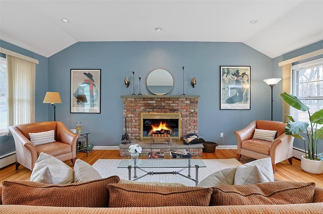 living room with lofted ceiling, a brick fireplace, baseboards, and wood finished floors