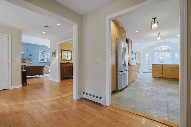 hallway featuring lofted ceiling, light wood-style flooring, visible vents, and a baseboard heating unit