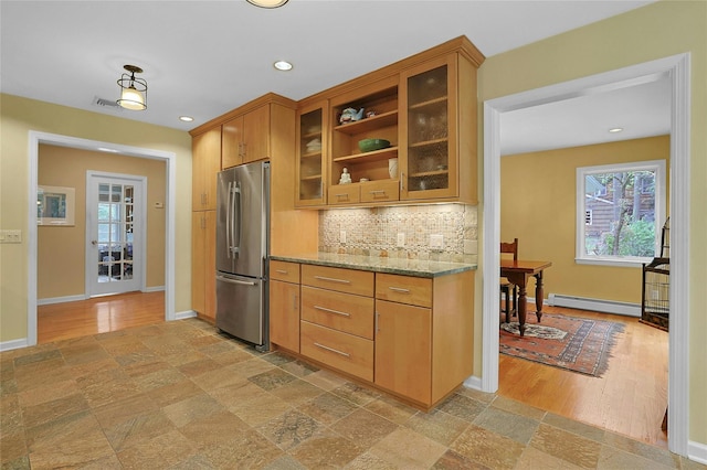 kitchen featuring a baseboard heating unit, tasteful backsplash, freestanding refrigerator, and baseboards