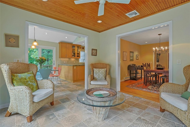 sitting room with stone tile flooring, wood ceiling, visible vents, and baseboards