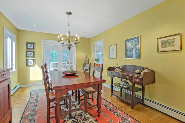 dining area featuring a chandelier, baseboard heating, light wood-type flooring, and baseboards