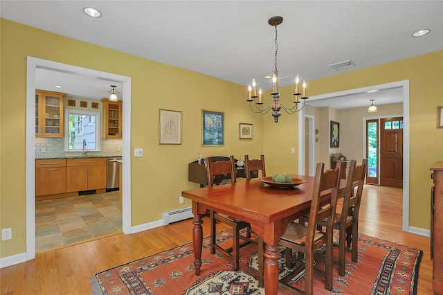 dining room featuring light wood-style floors, a baseboard radiator, visible vents, and baseboards