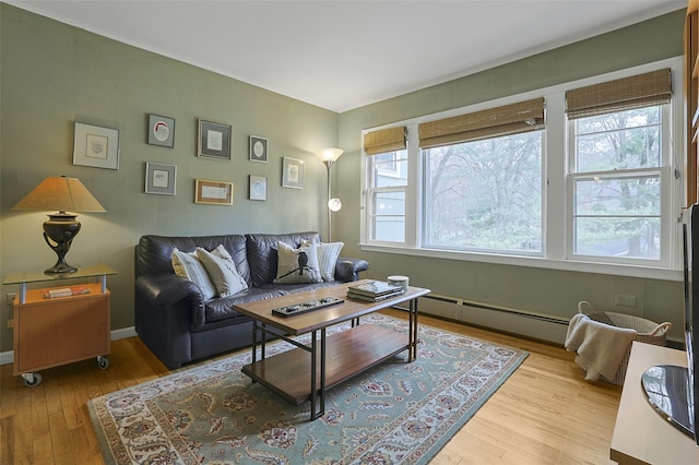 living area with hardwood / wood-style flooring, a baseboard radiator, and baseboards