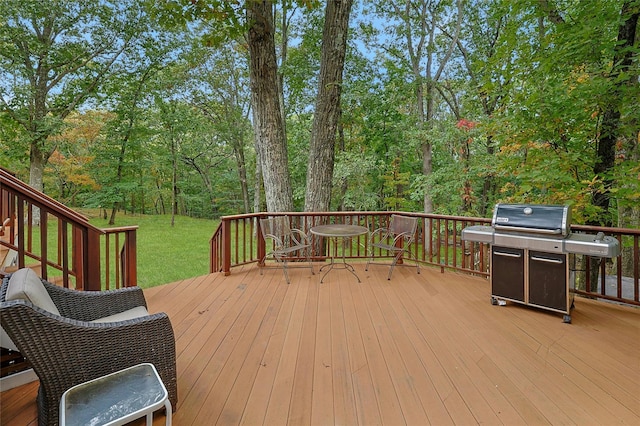 wooden deck featuring a lawn, a wooded view, and area for grilling