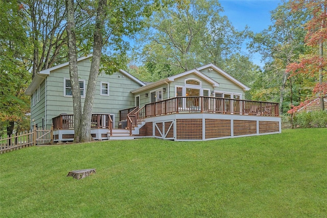 rear view of property featuring a yard, a wooden deck, and fence