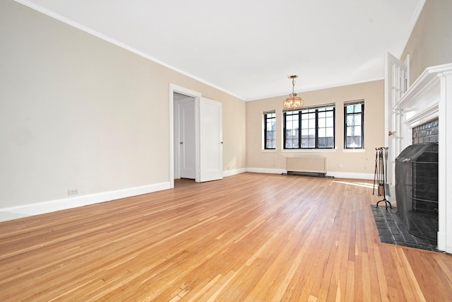 unfurnished living room featuring baseboards, light wood-style floors, ornamental molding, a brick fireplace, and an inviting chandelier