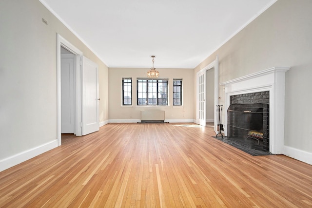 unfurnished living room featuring crown molding, a fireplace, light wood-style floors, a chandelier, and baseboards