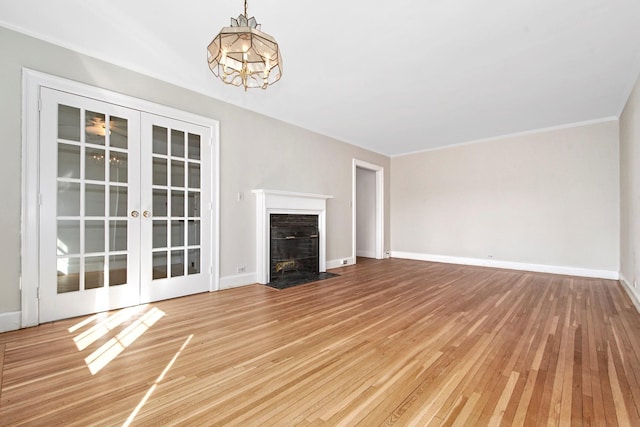 unfurnished living room featuring french doors, wood-type flooring, a fireplace with flush hearth, and baseboards