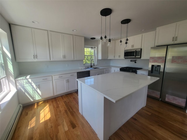 kitchen with white cabinets, stainless steel appliances, a kitchen island, and baseboard heating