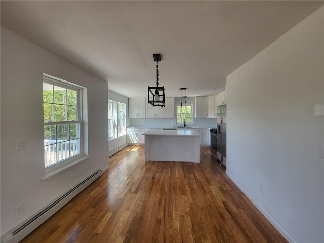 kitchen featuring a baseboard heating unit, white cabinets, light countertops, hanging light fixtures, and a center island