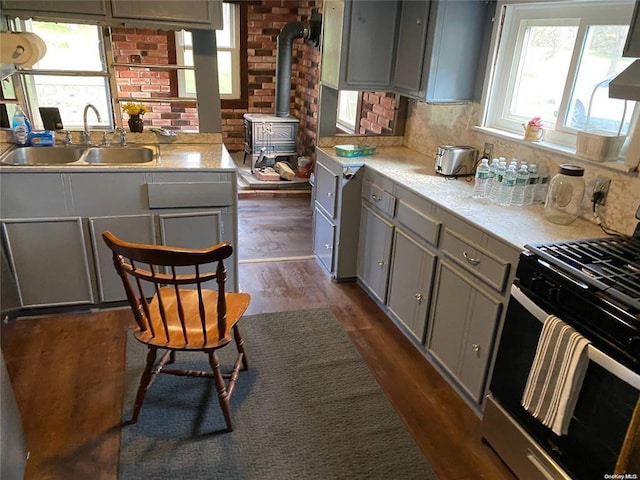 kitchen featuring dark wood-style flooring, light countertops, gray cabinetry, a sink, and gas stove