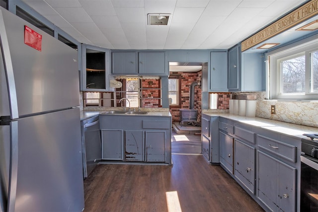 kitchen featuring dark wood-style floors, a sink, gray cabinetry, light countertops, and stainless steel appliances