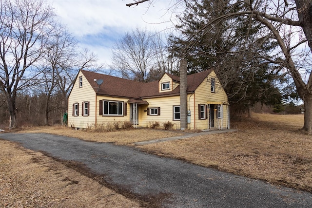 new england style home featuring aphalt driveway and a shingled roof