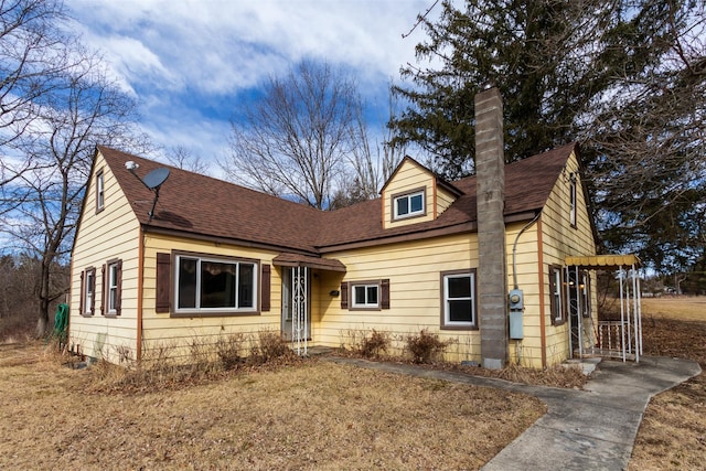 new england style home with roof with shingles and a chimney