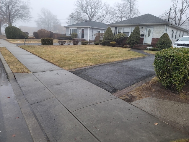 exterior space featuring a shingled roof, a front yard, brick siding, and entry steps