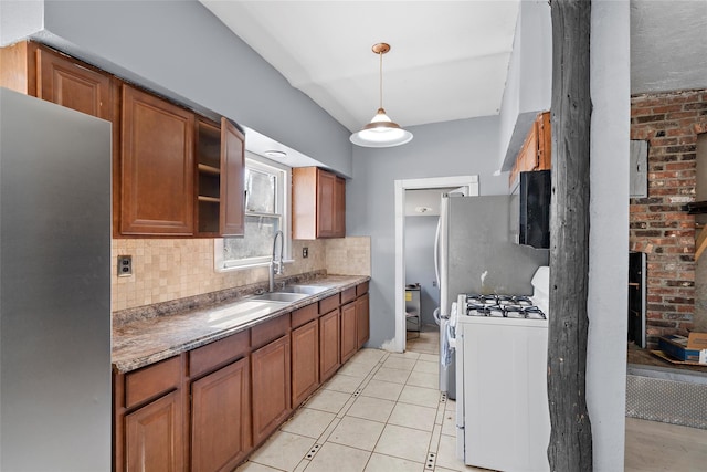 kitchen with white range with gas stovetop, decorative backsplash, brown cabinets, decorative light fixtures, and a sink