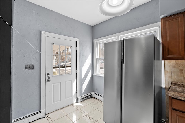 doorway featuring a textured wall, a baseboard radiator, and light tile patterned flooring