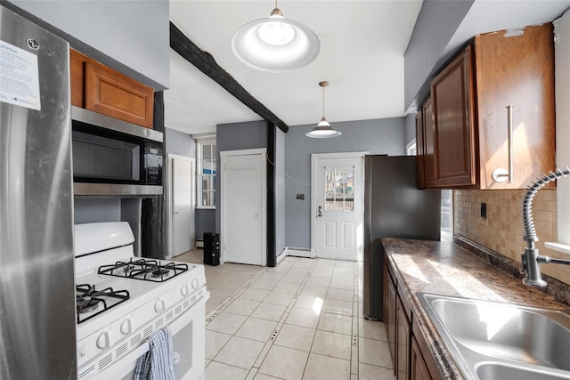 kitchen with tasteful backsplash, dark countertops, appliances with stainless steel finishes, brown cabinetry, and a sink