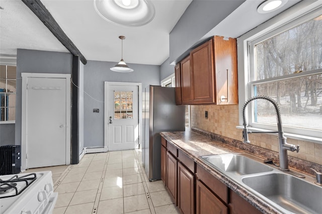 kitchen with a sink, hanging light fixtures, backsplash, brown cabinetry, and dark countertops