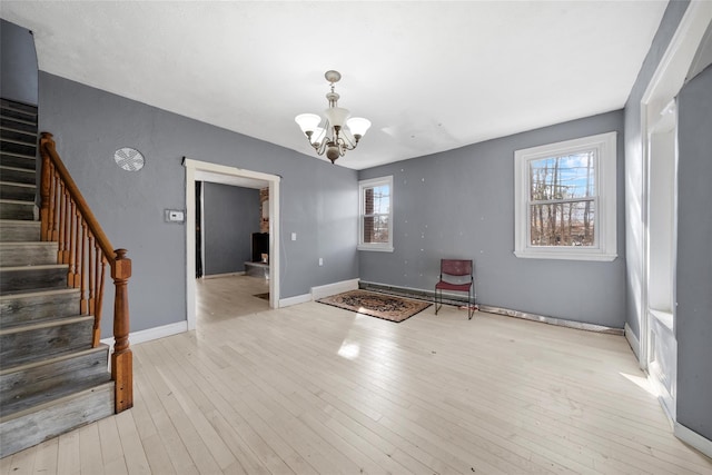 interior space with a chandelier, light wood-style flooring, baseboards, and stairs