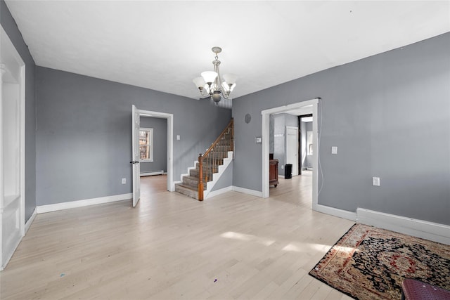 empty room featuring a notable chandelier, light wood finished floors, a baseboard radiator, baseboards, and stairs