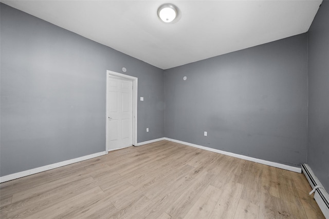 empty room with baseboard heating, light wood-style flooring, and baseboards