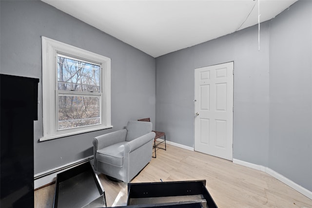 sitting room featuring light wood finished floors, baseboards, and a baseboard heating unit