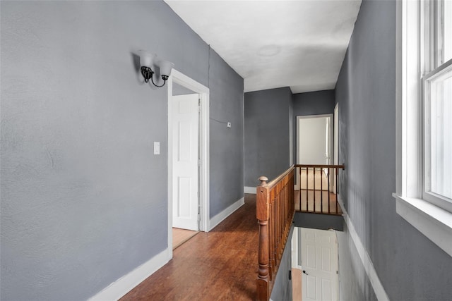 hall with baseboards, dark wood-type flooring, and an upstairs landing