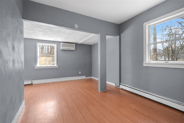 unfurnished room featuring baseboards, light wood-type flooring, a baseboard radiator, and a wall mounted air conditioner