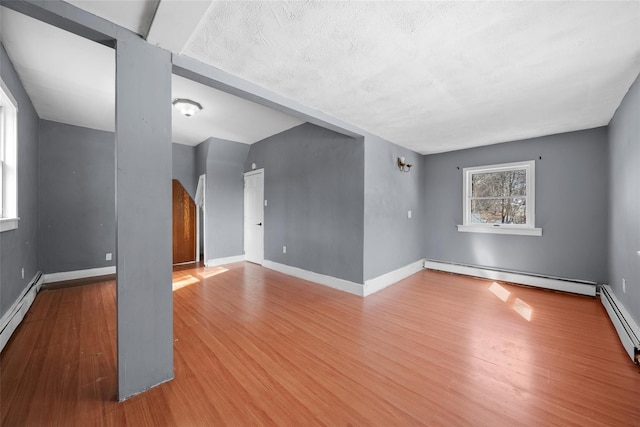 spare room with a baseboard radiator, baseboards, and wood finished floors