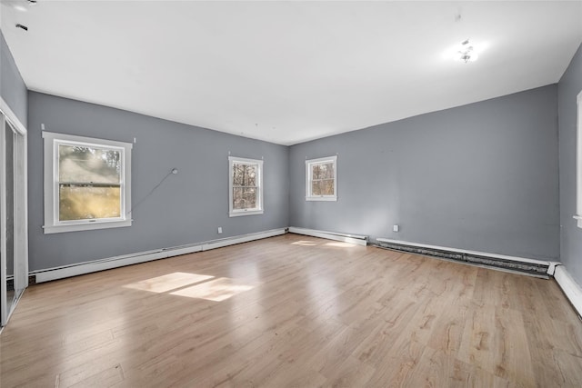 spare room with light wood finished floors, baseboards, and a baseboard heating unit