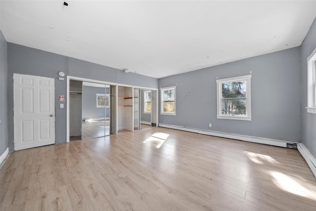 unfurnished room with light wood-style flooring and a baseboard heating unit