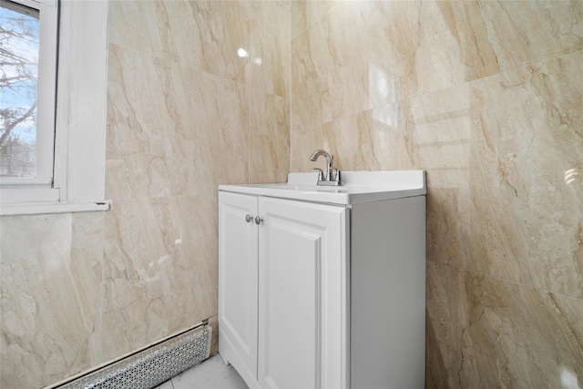 bathroom with baseboard heating, vanity, and tile walls