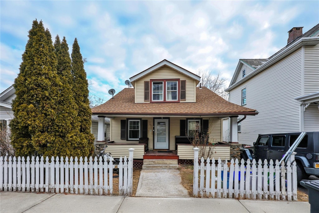 bungalow featuring roof with shingles, a porch, a fenced front yard, and a gate