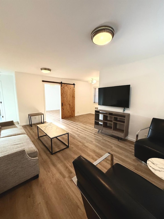 living area featuring wood finished floors, baseboards, and a barn door