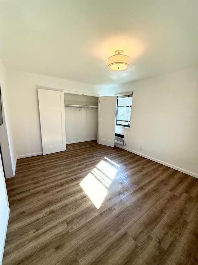 unfurnished bedroom with dark wood-style floors, baseboards, and a closet