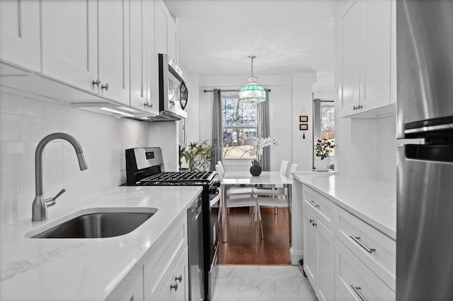 kitchen featuring decorative backsplash, appliances with stainless steel finishes, marble finish floor, white cabinetry, and a sink