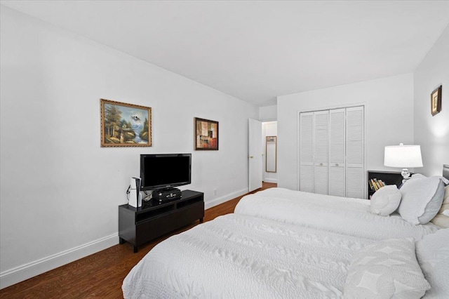 bedroom with dark wood-type flooring, a closet, and baseboards