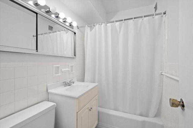 bathroom featuring a wainscoted wall, tile walls, toilet, shower / bath combo with shower curtain, and vanity