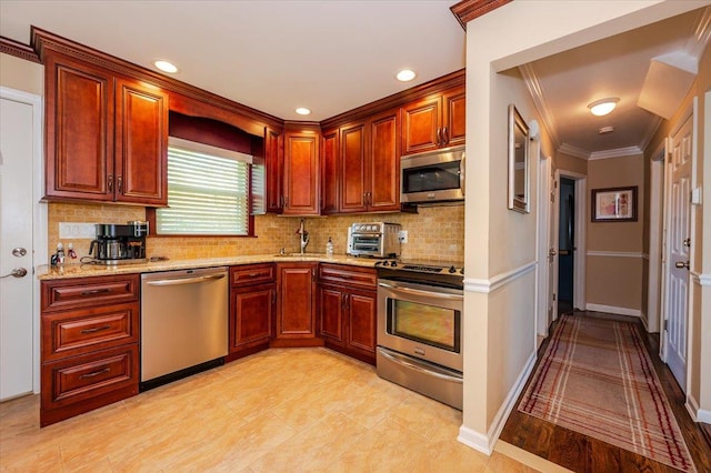 kitchen with appliances with stainless steel finishes, backsplash, light stone countertops, a sink, and crown molding