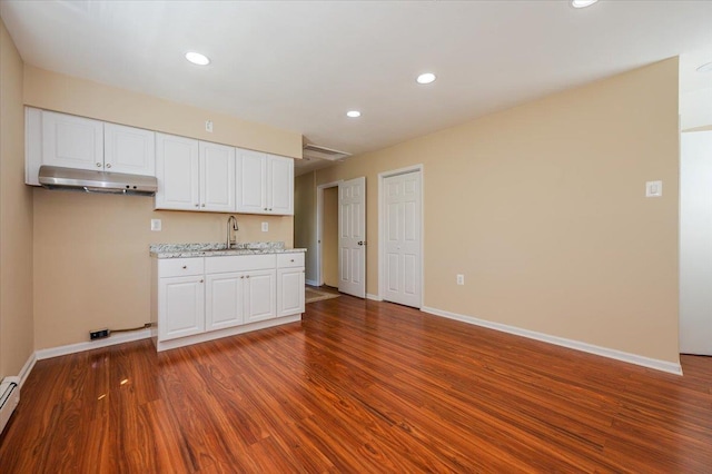 kitchen with a sink, under cabinet range hood, dark wood-style flooring, white cabinetry, and recessed lighting