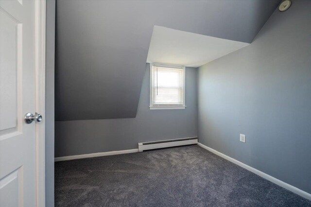 spare room featuring a baseboard radiator, dark carpet, a smoke detector, baseboards, and vaulted ceiling