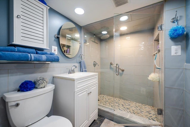 full bathroom featuring toilet, vanity, a stall shower, recessed lighting, and tile walls