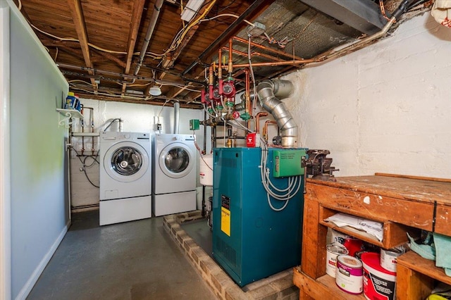 washroom with washing machine and clothes dryer, a heating unit, and baseboards