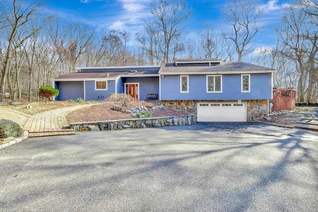 view of front of home featuring aphalt driveway, stone siding, and an attached garage